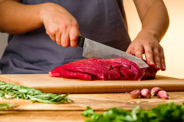 женщина режет свежее мясо на кухне - meat raw beef love стоковые фото и изображения
