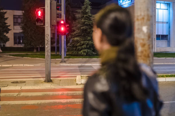 junge frau wartet an einer roten ampel, um die straße in der nacht zu überqueren - crossing zebra crossing crosswalk street stock-fotos und bilder