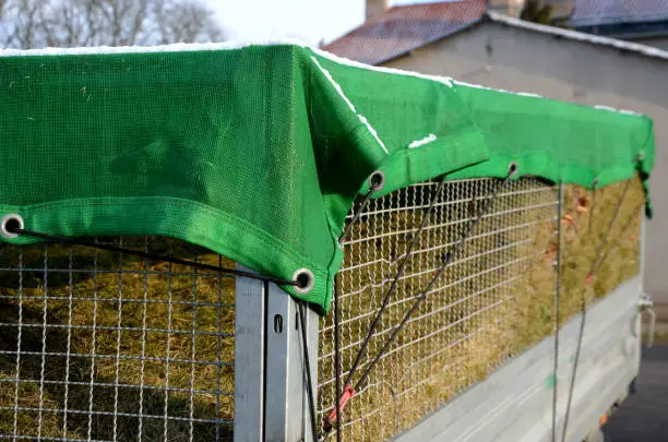 a properly covered pile of cut grass from garden maintenance on a trailer with a lattice superstructure for a larger capacity of the truck. gardening services