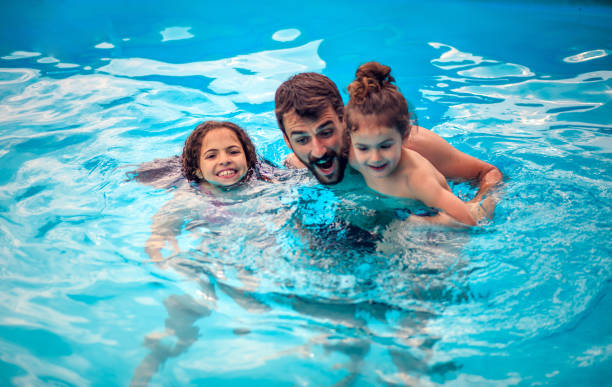 istock Father with kids playing in the pool. 1311424290