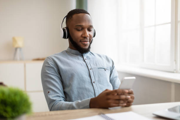 istock Relaxed Black Business Guy Using Smartphone Wearing Headphones At Workplace 1311424749