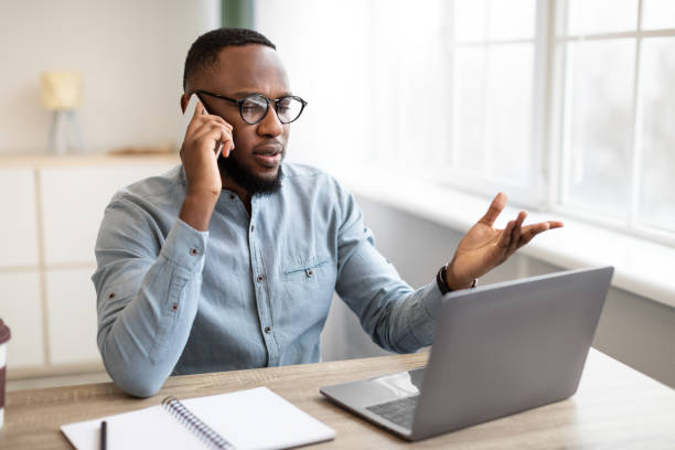 istock Serious Black Businessman Talking On Mobile Phone Sitting In Office 1311425327
