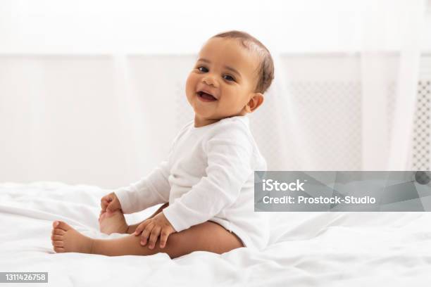 Porträt Von Afrikanischen Baby Kleinkind Lächelnd Sitzend Auf Dem Bett Innen Stockfoto und mehr Bilder von Glücklichsein