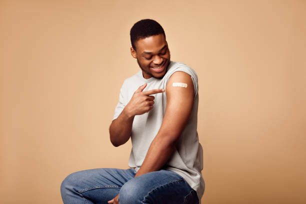 istock Vaccinated African Guy Pointing At Plaster On Arm, Beige Background 1311428611
