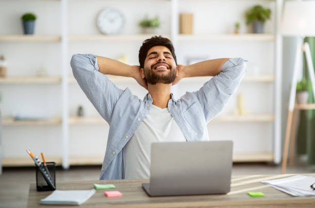istock Break in work. Relaxed arab man leaning back in chair, resting after work with laptop and holding hands behind head 1311428695