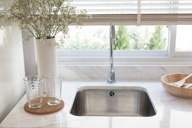 istock Clean new sink in stylish kitchen interior by the window. 1311428835