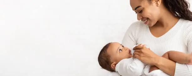 Photo of African Mother Feeding Baby Standing On White Background, Panorama, Cropped