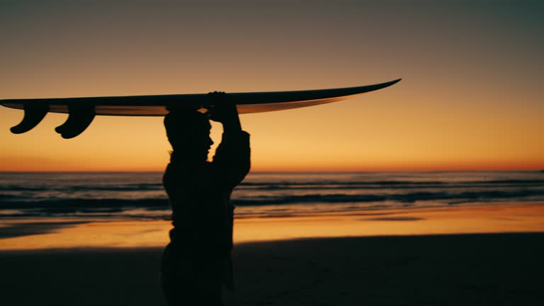 Woman carry surfboard on late sunset beach