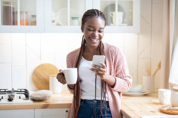 istock Hapy Black Lady Drinking Morning Coffee And Using Smartphone In Kitchen 1311431257