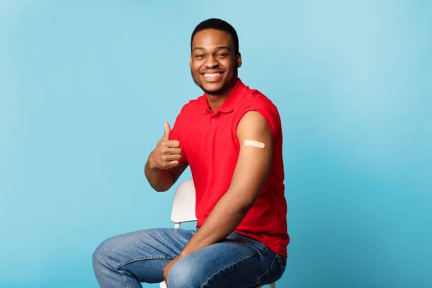 istock Happy Vaccinated African American Guy Gesturing Thumbs-Up Over Blue Background 1311432356