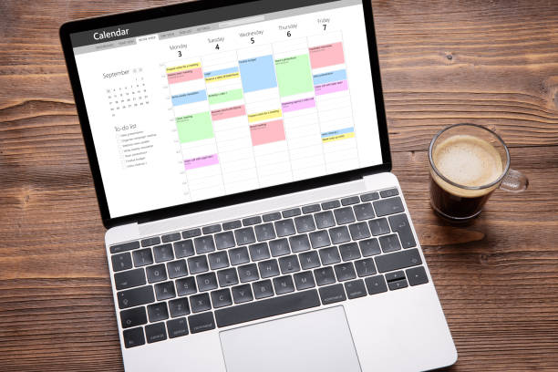 laptop mit kalender-app auf dem bildschirm gefüllt mit verschiedenen wöchentlichen terminen, besprechungen und aufgaben - terminplanung stock-fotos und bilder