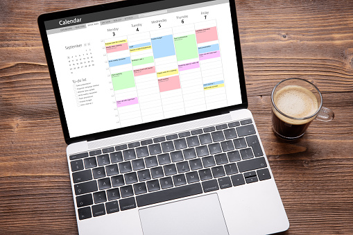 Portátil con aplicación de calendario en pantalla llena de diferentes citas semanales, reuniones y tareas photo