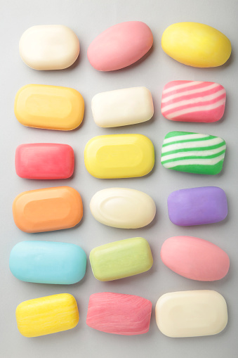 Different soaps in different soap dishes. A lot of solid soap for hygiene and cleanliness. Colorful soap and remnants are scattered on grey background. Vertical foto