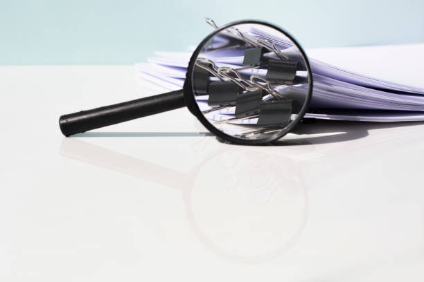 istock Scanning business documents. Magnifying glass on the stack of documents. 1311436936