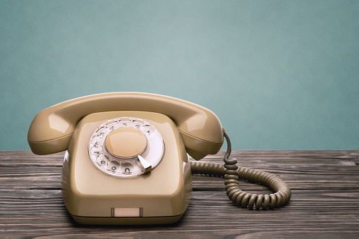 El teléfono viejo se encuentra en las tablas de madera aisladas sobre un fondo azul photo
