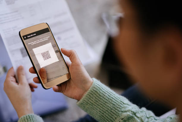 istock Mid adult woman scanning QR code with smart phone 1311437031