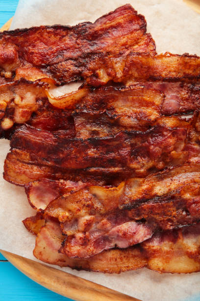 istock Bacon fried slices on cutting board on blue background. Top view 1311437033