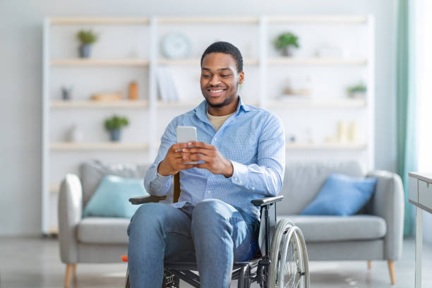 istock Disabled black man in wheelchair using smartphone, browsing web or watching movie at home 1311437345