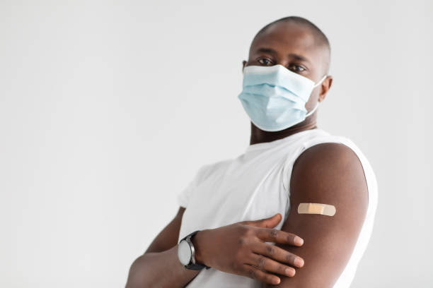 istock Vaccination and immunization. African american man wearing protective mask and showing plaster after injection 1311437516