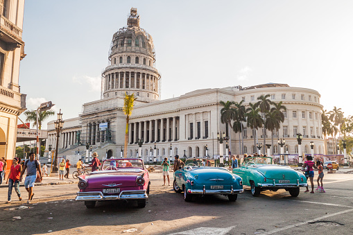 Havana, CUba - Feb 20, 2016: Colorful vintage cars wait for tourists in Parque Central in Havana in front of the National Capitol.