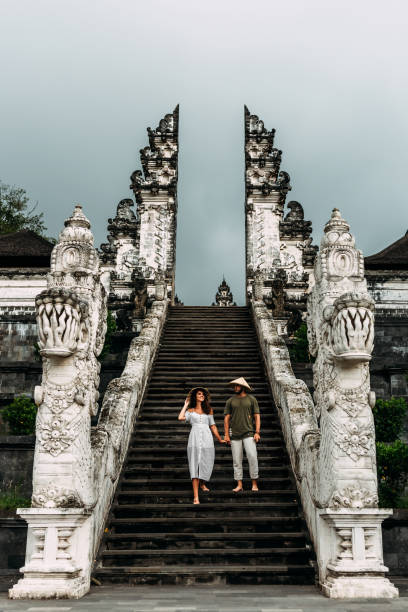 A couple stands on the stairs of the Baltic temple. Man and woman traveling in Indonesia. Couple at the Bali gate. The couple travels the world. Tourists in Bali. Copy space. Vertical photo stock photo