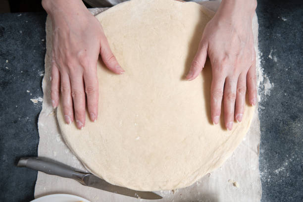 istock Women's hands knead the dough from wheat flour 1311443143