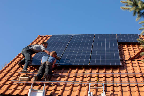Workers installing solar electric panels on a house roof stock photo