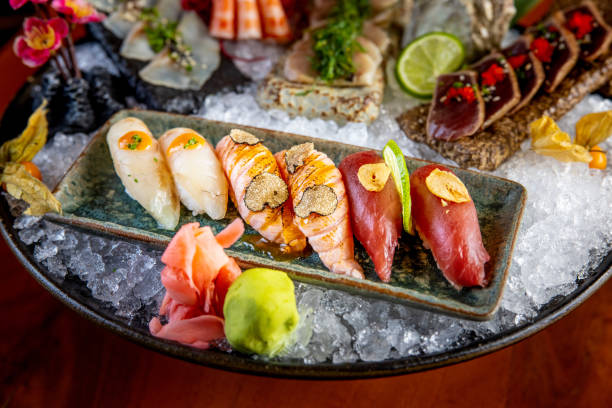 Close-up on nigiri with ginger and wasabi in serving dish full of ice Close-up on nigiri with truffle garnish, ginger and wasabi on the side, serving dish full of ice with Japanese raw food delicacies tartuffo stock pictures, royalty-free photos & images