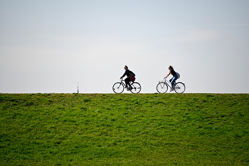 Duesseldorf, Germany, March 30, 2021 - Silhouette of cyclists on the Rhine dike in Duesseldorf