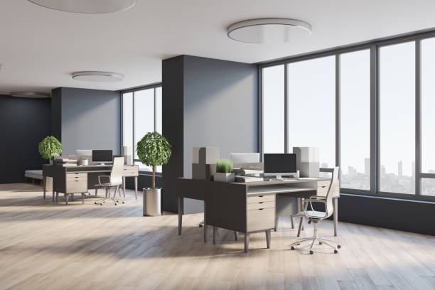 istock Modern open space office with eco style interior design, wooden table, floor, tree in a flowerpot, dark walls and huge window with city view 1311450430