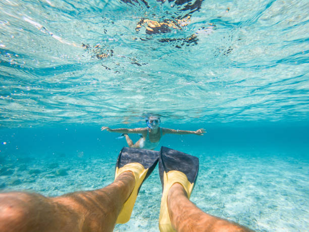 They explore the reef around the atoll in the Maldives, people on vacations, Man's perspective, woman on background