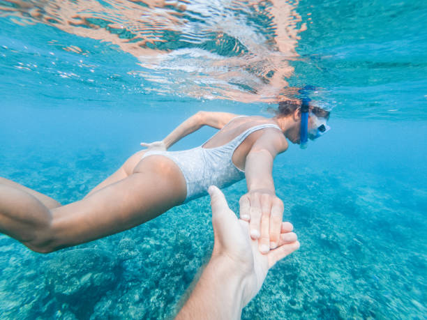 istock Woman snorkels underwater, couple holding hands 1311453441
