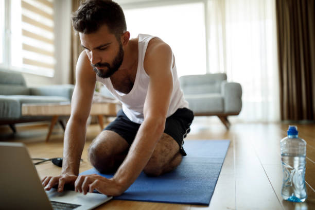 istock Young man searching online exercise classes at home 1311454634