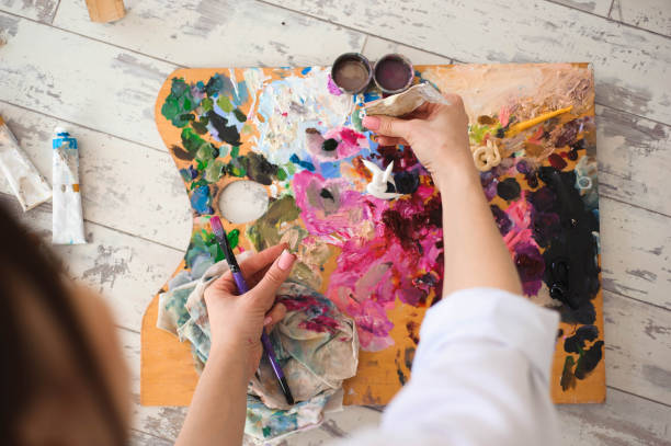 istock Young female student having classes at art studio, trying to mix different watercolors on cardboard. 1311454795