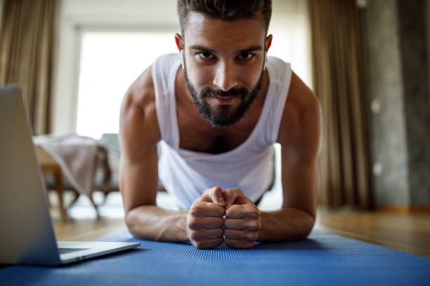 istock Smiling young man with bluetooth headphones exercising at home 1311454846