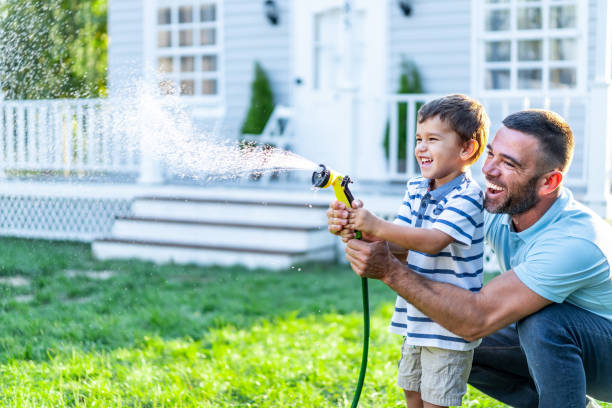 istock Father splashing water and having fun with son on back yard 1311456094
