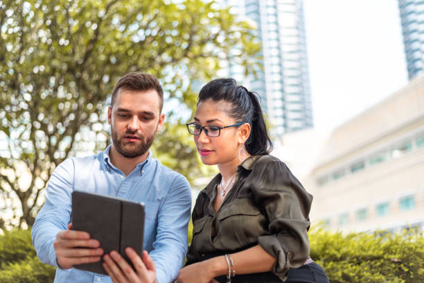 istock Couple sitting in park and using laptop 1311456227