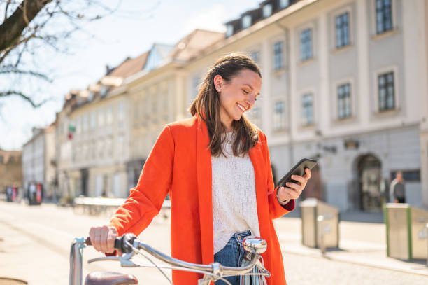 istock Young cheerful woman with bicycle using a smart phone outdoors 1311457864