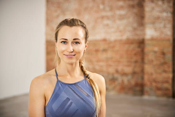 Beautiful Blond Smiling Female Yoga Instructor Portrait of beautiful smiling female yoga instructor. Blond woman is in sports clothing. She is in exercise room. yoga instructor stock pictures, royalty-free photos & images