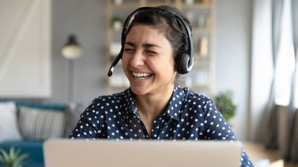 istock Indian female wear headset laughing during video call communication 1311463189