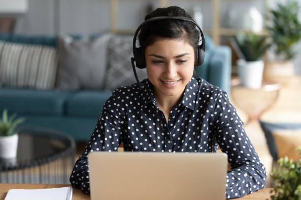 istock Indian woman wearing headset participates in educational webinar using laptop 1311463195