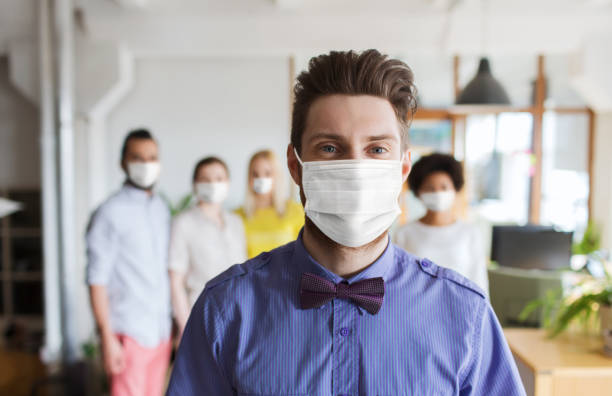istock young man in mask over creative team at office 1311463767