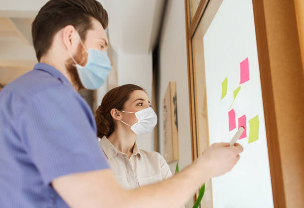 istock team in masks with stickers on glass at office 1311464323