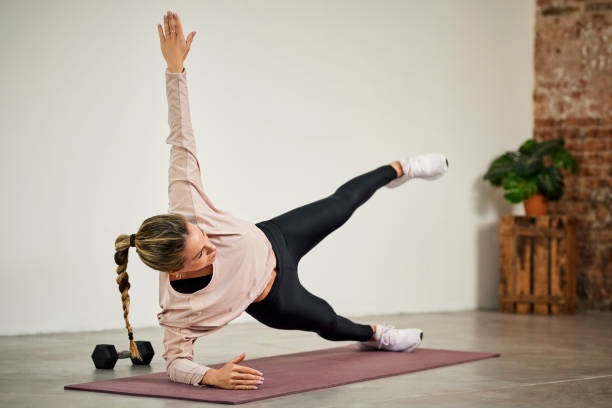 Young Woman Exercising While Doing Side Plank stock photo