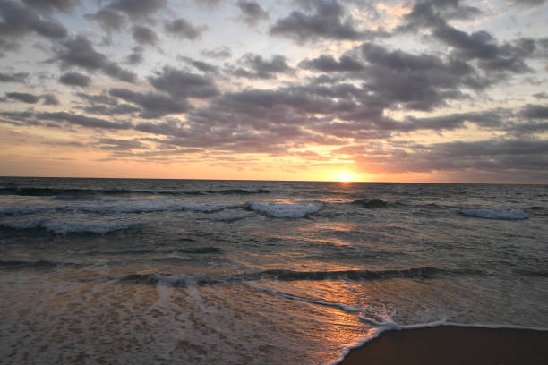 Picturesque seascape sun at sunset behind beautiful clouds on a summer evening on the beach