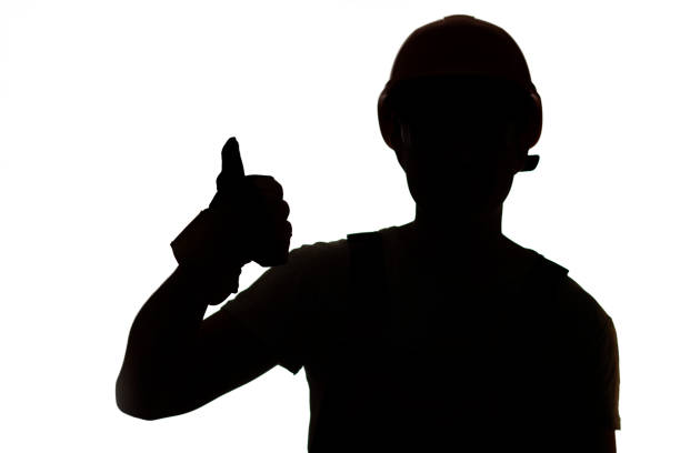 Young construction worker silhouette in hard hat showing thumbs up class sign on white isolated studio background