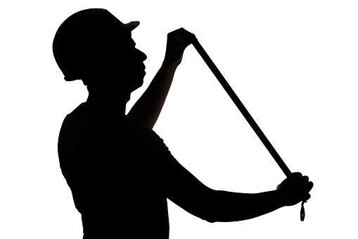 silhouette figure of builder in hard hat with meter worker measures , worker in process of measuring, concept male profession on white isolated background