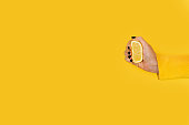 Woman squeezing a half lemon on a yellow background