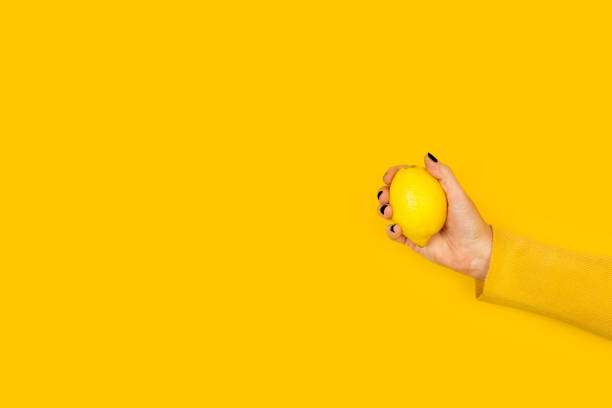 istock Woman holding a lemon on a yellow background 1311470615