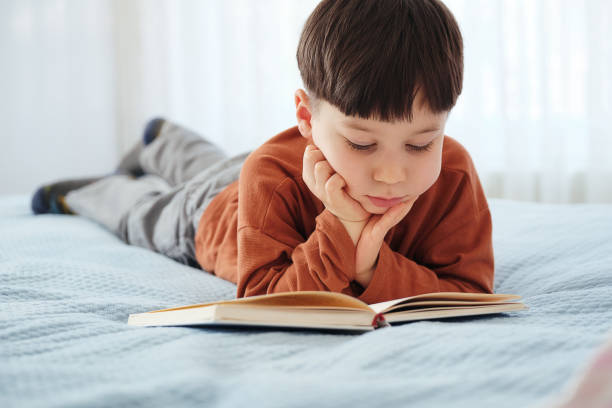 istock 4-5 years old child reading book at home. Lying down at bed 1311471611